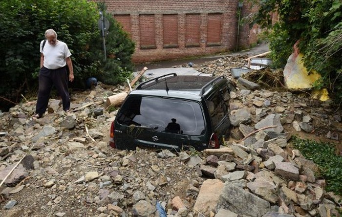 A man walks past a car immersed in debris after floods caused major damage in Hagen, western Germany, on July 15, 2021. - Heavy rains and floods lashing western Europe have killed at least 42 people in Germany and left many more missing, as rising waters led several houses to collapse. (Photo by INA FASSBENDER / AFP)