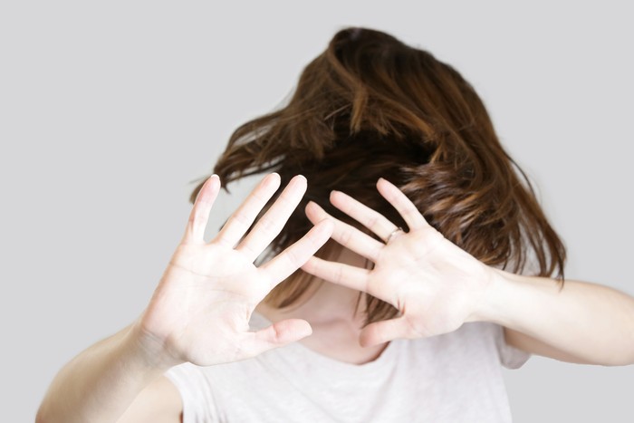 Self defense, studio portrait of scared woman raising hands up in defense
