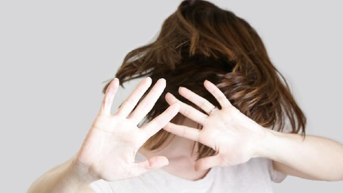 Self defense, studio portrait of scared woman raising hands up in defense