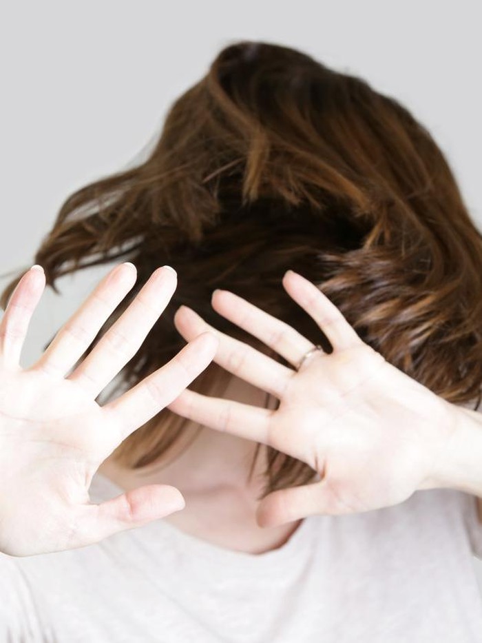 Self defense, studio portrait of scared woman raising hands up in defense