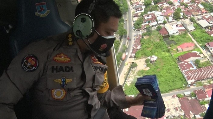 Kabid Humas Polda Sumut Kombes Hadi Wahyudi saat menebar brosur dari helikopter (dok Humas Polda Sumut)