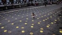 Seorang anak berlari melewati penanda jarak sosial di jalan, di Manila, Filipina. Getty Images/Ezra Acayan  