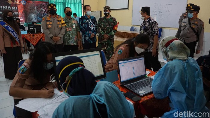 Vaksinasi COVID-19 di Kabupaten Mojokerto mulai menyasar pelajar SMA/SMK. Petugas gabungan polisi, TNI dan Dinas Kesehatan menerapkan strategi jemput bola ke sekolah untuk mempercepat vaksinasi.