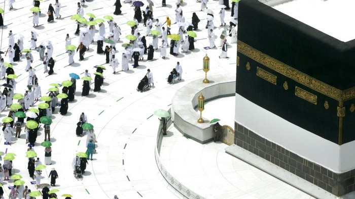 A Saudi police woman, left, who is recently deployed to the service, at top left, stands alert in front of the Al-Safa mountain, as pilgrims pray at the Grand Mosque, at the Grand Mosque, a day before the annual hajj pilgrimage, Saturday, July 17, 2021. The pilgrimage to Mecca required once in a lifetime of every Muslim who can afford it and is physically able to make it, used to draw more than 2 million people. But for a second straight year it has been curtailed due to the coronavirus with only vaccinated people in Saudi Arabia able to participate. (AP Photo/Amr Nabil)