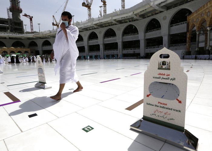 A Saudi police woman, left, who is recently deployed to the service, at top left, stands alert in front of the Al-Safa mountain, as pilgrims pray at the Grand Mosque, at the Grand Mosque, a day before the annual hajj pilgrimage, Saturday, July 17, 2021. The pilgrimage to Mecca required once in a lifetime of every Muslim who can afford it and is physically able to make it, used to draw more than 2 million people. But for a second straight year it has been curtailed due to the coronavirus with only vaccinated people in Saudi Arabia able to participate. (AP Photo/Amr Nabil)