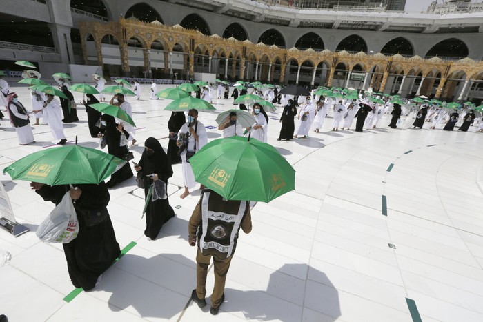 A Saudi police woman, left, who is recently deployed to the service, at top left, stands alert in front of the Al-Safa mountain, as pilgrims pray at the Grand Mosque, at the Grand Mosque, a day before the annual hajj pilgrimage, Saturday, July 17, 2021. The pilgrimage to Mecca required once in a lifetime of every Muslim who can afford it and is physically able to make it, used to draw more than 2 million people. But for a second straight year it has been curtailed due to the coronavirus with only vaccinated people in Saudi Arabia able to participate. (AP Photo/Amr Nabil)