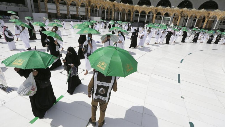 A Saudi police woman, left, who is recently deployed to the service, at top left, stands alert in front of the Al-Safa mountain, as pilgrims pray at the Grand Mosque, at the Grand Mosque, a day before the annual hajj pilgrimage, Saturday, July 17, 2021. The pilgrimage to Mecca required once in a lifetime of every Muslim who can afford it and is physically able to make it, used to draw more than 2 million people. But for a second straight year it has been curtailed due to the coronavirus with only vaccinated people in Saudi Arabia able to participate. (AP Photo/Amr Nabil)