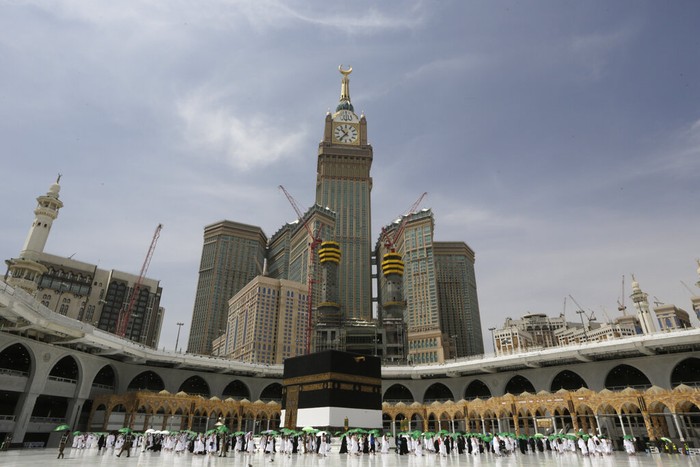A Saudi police woman, left, who is recently deployed to the service, at top left, stands alert in front of the Al-Safa mountain, as pilgrims pray at the Grand Mosque, at the Grand Mosque, a day before the annual hajj pilgrimage, Saturday, July 17, 2021. The pilgrimage to Mecca required once in a lifetime of every Muslim who can afford it and is physically able to make it, used to draw more than 2 million people. But for a second straight year it has been curtailed due to the coronavirus with only vaccinated people in Saudi Arabia able to participate. (AP Photo/Amr Nabil)