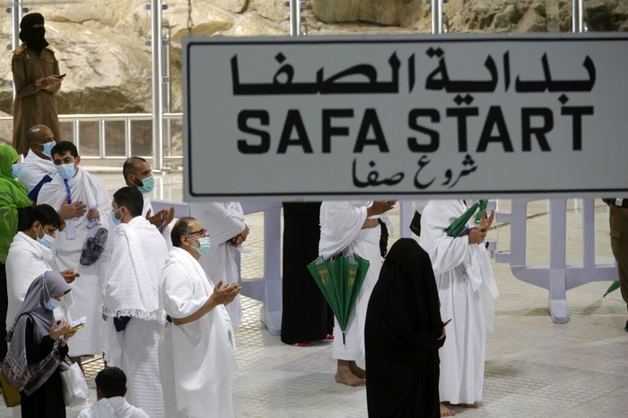 A Saudi police woman, left, who is recently deployed to the service, at top left, stands alert in front of the Al-Safa mountain, as pilgrims pray at the Grand Mosque, at the Grand Mosque, a day before the annual hajj pilgrimage, Saturday, July 17, 2021. The pilgrimage to Mecca required once in a lifetime of every Muslim who can afford it and is physically able to make it, used to draw more than 2 million people. But for a second straight year it has been curtailed due to the coronavirus with only vaccinated people in Saudi Arabia able to participate. (AP Photo/Amr Nabil)