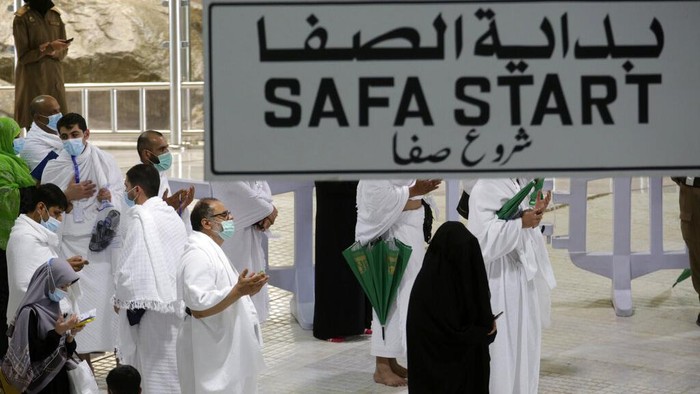 A Saudi police woman, left, who is recently deployed to the service, at top left, stands alert in front of the Al-Safa mountain, as pilgrims pray at the Grand Mosque, at the Grand Mosque, a day before the annual hajj pilgrimage, Saturday, July 17, 2021. The pilgrimage to Mecca required once in a lifetime of every Muslim who can afford it and is physically able to make it, used to draw more than 2 million people. But for a second straight year it has been curtailed due to the coronavirus with only vaccinated people in Saudi Arabia able to participate. (AP Photo/Amr Nabil)