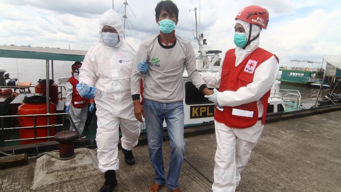 Potret Evakuasi Korban Kapal Tenggelam di Perairan Kalbar Dua petugas medis menuntun Purwanto (tengah), awak Kapal Motor Usaha Abadi yang selamat dari kecelakaan kapal tenggelam saat tiba di dermaga Pelabuhan Kantor Kesyahbandaran dan Otoritas Pelabuhan Pontianak, Kalimantan Barat, Jumat (16/7/2021). Hingga saat ini Basarnas masih melakukan pencarian terhadap 44 awak dari 16 kapal motor yang tenggelam di Perairan Kalbar akibat cuaca buruk pada Selasa (13/7/2021) malam dan Rabu pagi (14/7/2021). ANTARA FOTO/Jessica Helena Wuysang/hp.