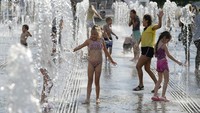Anak-anak bermain air mancur di taman dekat tanggul Sungai Moskow di Moskow, Rusia. AP Photo/Pavel Golovkin  