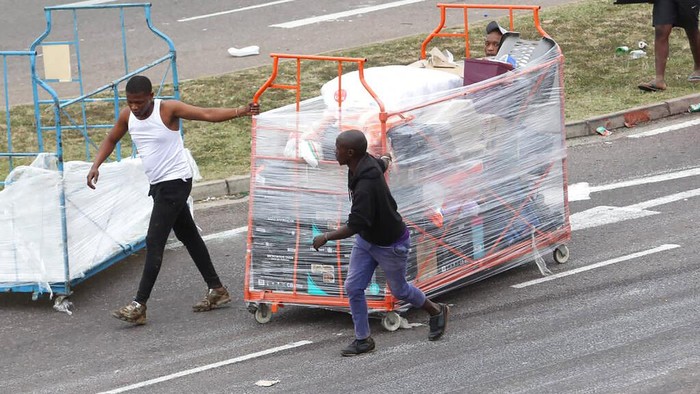Waduh! Ratusan Toko Dijarah Saat Kerusuhan di Afrika Selatan Fast food staff members collect kitchen equipment that was discarded by looters at a trashed shopping mall in Soweto in Johannesburg, South Africa, Tuesday, July 13, 2021. South Africa's rioting continued Tuesday with the death toll rising to 32 as police and the military struggle to quell the violence in Gauteng and KwaZulu-Natal provinces. The violence started in various parts of KwaZulu-Natal last week when Zuma began serving a 15-month sentence for contempt of court. (AP Photo/Themba Hadebe)