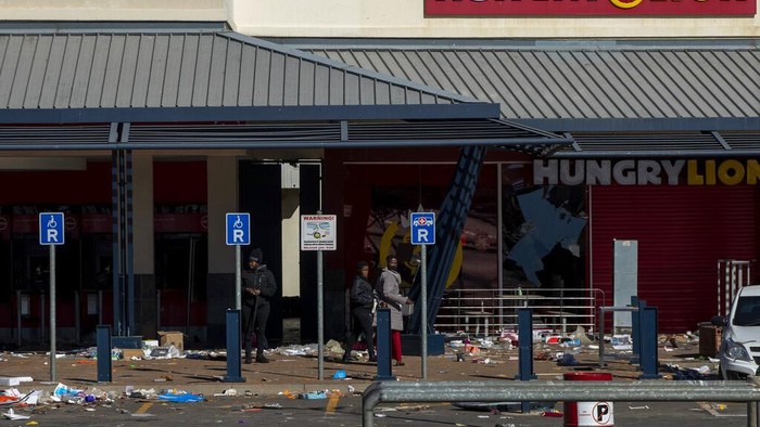 Fast food staff members collect kitchen equipment that was discarded by looters at a trashed shopping mall in Soweto in Johannesburg, South Africa, Tuesday, July 13, 2021. South Africa's rioting continued Tuesday with the death toll rising to 32 as police and the military struggle to quell the violence in Gauteng and KwaZulu-Natal provinces. The violence started in various parts of KwaZulu-Natal last week when Zuma began serving a 15-month sentence for contempt of court. (AP Photo/Themba Hadebe)