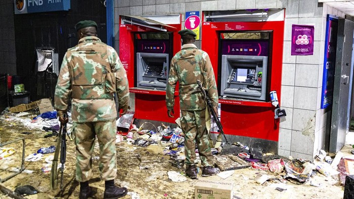 Soldiers guard an autobahn at the Bara taxi rank shops in Soweto, Johannesburg, Monday, July 12, 2021. Police say six people are dead and more than 200 have been arrested amid escalating violence during rioting that broke out following the imprisonment of South Africa's former President Jacob Zuma. (AP Photo/Ali Greeff)