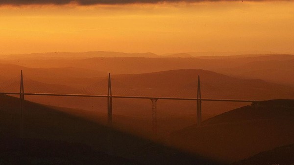 Penampakan matahari terbenam di jembatan Millau Viaduct, Prancis. Jembatan kabel yang mulai dibangun pada akhir tahun 2001 dan dibuka pada tanggal 14 Desember 2004 ini memiliki tinggi tiang mencapai 343 meter. Jembatan ini pun merupakan salah satu jembatan tertinggi di dunia. Pascal Le Segretain/Getty Images. Penampakan matahari terbenam di jembatan Millau Viaduct, Prancis. Jembatan kabel yang mulai dibangun pada akhir tahun 2001 dan dibuka pada tanggal 14 Desember 2004 ini memiliki tinggi tiang mencapai 343 meter. Jembatan ini pun merupakan salah satu jembatan tertinggi di dunia. Pascal Le Segretain/Getty Images.