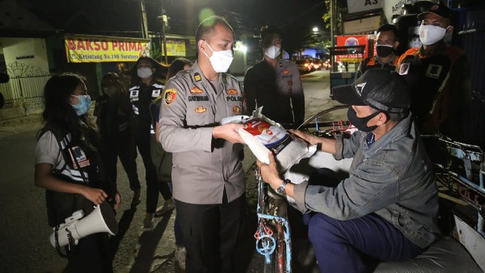 Petugas gabungan menggelar patroli skala besar di Surabaya. Selain merazia pelanggar prokes, mereka juga membagikan sembako ke warga terdampak PPKM Darurat.