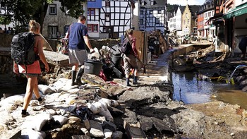 Warga yang selamat mencoba melihat area rumah mereka yang rusak. Foto: AP/Boris Roessler