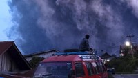 Sejumlah pengendara melintas di Jalan Karo-Langkat dengan latar belakang Gunung Sinabung yang menyemburkan material vulkanik di Desa Kutarayat, Naman Teran, Karo, Sumatera Utara, Senin (19/7/2021). 