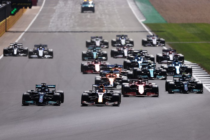 NORTHAMPTON, ENGLAND - JULY 18: Lewis Hamilton of Great Britain driving the (44) Mercedes AMG Petronas F1 Team Mercedes W12 and Max Verstappen of the Netherlands driving the (33) Red Bull Racing RB16B Honda lead the field into turn one at the start during the F1 Grand Prix of Great Britain at Silverstone on July 18, 2021 in Northampton, England. (Photo by Lars Baron/Getty Images)