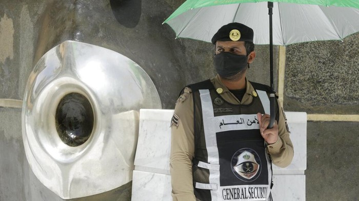 A Saudi policeman stands alert beside Al-Hajar al-Aswad, the black stone, at right, a Muslim holy relic which according to Islamic tradition dates back to the time of Adam and Eve, at the Grand Mosque, a day before the annual hajj pilgrimage, Saturday, July 17, 2021. The pilgrimage to Mecca required once in a lifetime of every Muslim who can afford it and is physically able to make it, used to draw more than 2 million people. But for a second straight year it has been curtailed due to the coronavirus with only vaccinated people in Saudi Arabia able to participate. (AP Photo/Amr Nabil)