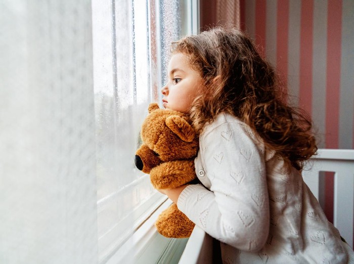 Little cute girl is watching from window to the rain with sadness get bored. . High quality photo