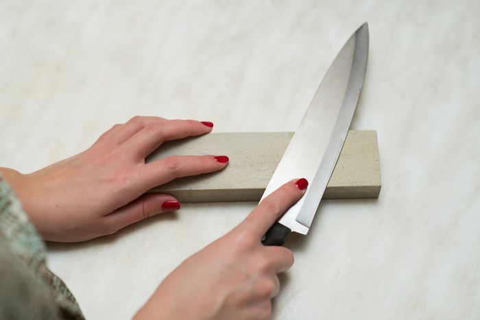 knife, whetstone and female hands. Woman and male work