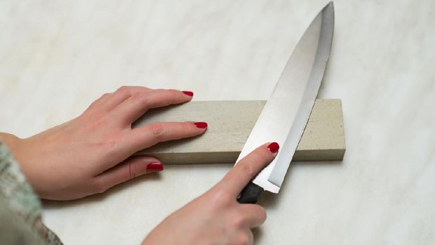 knife, whetstone and female hands. Woman and male work