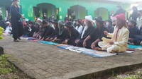 Para jemaah melaksanakan salat dengan mengenakan pakaian serba hitam dan menggunakan masker, namun tidak ada jarak di antara mereka.