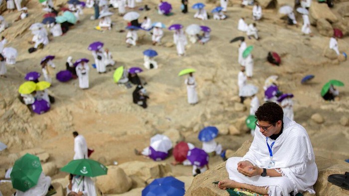 A Muslim pilgrim prays on top of the rocky hill known as the Mountain of Mercy, on the Plain of Arafat, during the annual hajj pilgrimage, near the holy city of Mecca, Saudi Arabia, Monday, July 19, 2021. The coronavirus has taken its toll on the hajj for a second year running. What once drew some 2.5 million Muslims from all walks of life from across the globe, the hajj pilgrimage is now almost unrecognizable in scale. (AP Photo/Amr Nabil)