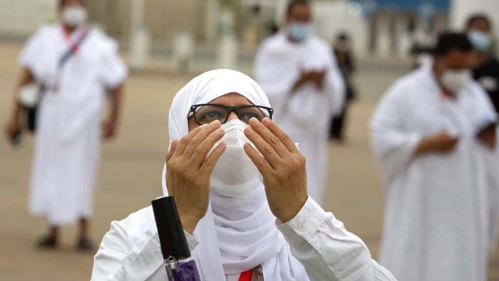 Tangisan Jemaah Haji di Tengah Pandemi A Muslim pilgrim prays in front of the rocky hill known as Mountain of Mercy, on the Plain of Arafat, during the annual hajj pilgrimage, near the holy city of Mecca, Saudi Arabia, Monday, July 19, 2021. Tens of thousands of vaccinated Muslim pilgrims circled Islam's holiest site in Mecca on Sunday, but remained socially distanced and wore masks as the coronavirus takes its toll on the hajj for a second year running. What once drew some 2.5 million Muslims from all walks of life from across the globe, the hajj pilgrimage is now almost unrecognizable in scale. (AP Photo/Amr Nabil)