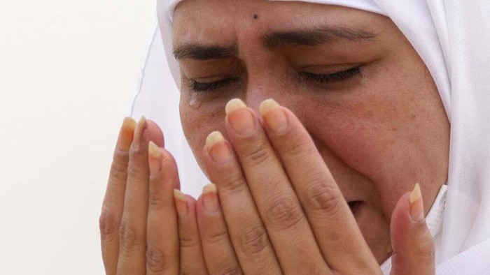 Tangisan Jemaah Haji di Tengah Pandemi A Muslim pilgrim prays in front of the rocky hill known as Mountain of Mercy, on the Plain of Arafat, during the annual hajj pilgrimage, near the holy city of Mecca, Saudi Arabia, Monday, July 19, 2021. Tens of thousands of vaccinated Muslim pilgrims circled Islam's holiest site in Mecca on Sunday, but remained socially distanced and wore masks as the coronavirus takes its toll on the hajj for a second year running. What once drew some 2.5 million Muslims from all walks of life from across the globe, the hajj pilgrimage is now almost unrecognizable in scale. (AP Photo/Amr Nabil)