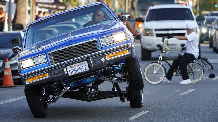 Aksi Mobil Lowrider Mengaspal di Jalanan Los Angeles A photographer captures a detail shot of a vintage vehicle cruising on Sunset Blvd., in the Echo Park neighborhood of Los Angeles late Sunday afternoon July 18, 2021. (AP Photo/Damian Dovarganes)