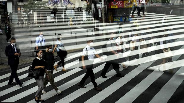 Aktivitas warga di Tokyo, Jepang Commuters are reflected in a bus window as they cross the street Thursday, July 15, 2021, in Tokyo. The pandemic-delayed 2020 Summer Olympics open on July 23 without spectators at most venues. (AP Photo/Jae C. Hong)