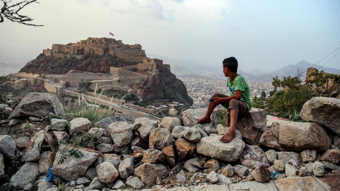 A boy looks at a giant Yemeni flag flying at the historic 12th cehntury citadel of al-Qahira in Yemens third city of Taez, on July 18, 2021, ahead of celebrations of the Muslim holiday of Eid al-Adha. - Known as the 