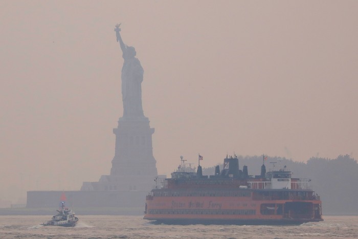 Boats make their way in front of the Statue of Liberty, which is seen through a cover of wildfire smoke in New York City, New York, U.S., July 20, 2021. REUTERS/Andrew Kelly