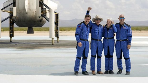 Oliver Daemen, from left, Jeff Bezos, founder of Amazon and space tourism company Blue Origin, Wally Funk and Bezos' brother Mark pose for photos in front of the Blue Origin New Shepard rocket, left rear, after their launch from the spaceport near Van Horn, Texas, Tuesday, July 20, 2021. (AP Photo/Tony Gutierrez)