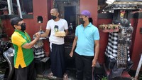 Warga muslim (kanan) memberikan daging kurban kepada seorang Pecalang atau petugas keamanan adat Bali pada Hari Raya Idul Adha 1442 H di kawasan Padangsambian, Denpasar, Bali, Selasa (20/7/2021).