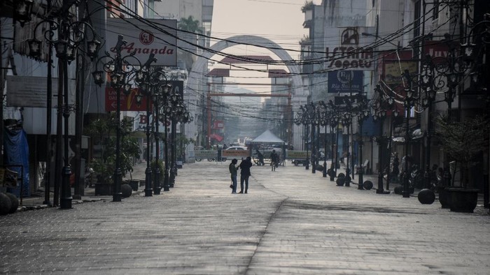 Sepinya Kota Bandung Kala PPKM Diperpanjang Warga melintas di samping spanduk pengumuman jam operasional di salah satu pusat perbelanjaan di Kota Bandung, Jawa Barat, Rabu (21/7/2021). Menindaklanjuti arahan Presiden Joko Widodo, Pemerintah Kota Bandung kembali memperpanjang PPKM hingga 25 Juli mendatang dengan melonggarkan beberapa kebijakan guna mencegah penyebaran COVID-19. ANTARA FOTO/Raisan Al Farisi/foc.