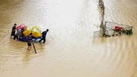 Warga menyeberangi banjir dengan menggunakan gerobak dorong yang dikendalikan oleh jasa manusia. Tak jauh berbeda dengan di Indonesia saat terjadi banjir. Foto: AP/Zhu Xiang