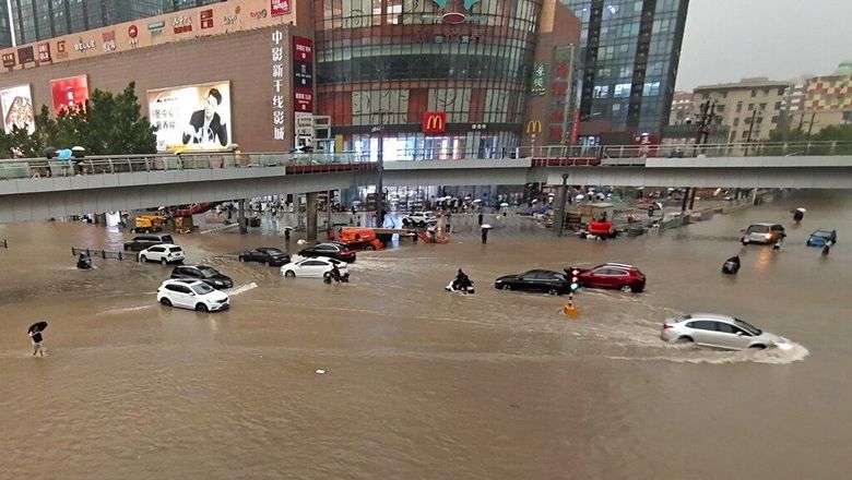 People move through flood water after a heavy downpour in Zhengzhou city, central Chinas Henan province on Tuesday, July 20, 2021. Heavy flooding has hit central China following unusually heavy rains, with the subway system in the city of Zhengzhou inundated with rushing water and thousands of residents having to be relocated. (Chinatopix Via AP)