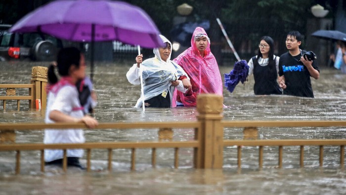 People move through flood water after a heavy downpour in Zhengzhou city, central Chinas Henan province on Tuesday, July 20, 2021. Heavy flooding has hit central China following unusually heavy rains, with the subway system in the city of Zhengzhou inundated with rushing water and thousands of residents having to be relocated. (Chinatopix Via AP)