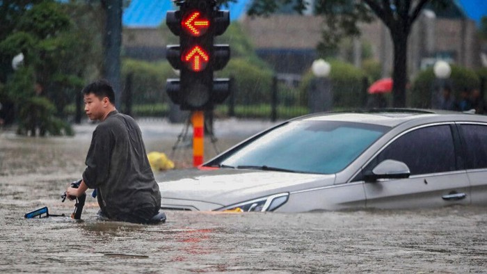 People move through flood water after a heavy downpour in Zhengzhou city, central Chinas Henan province on Tuesday, July 20, 2021. Heavy flooding has hit central China following unusually heavy rains, with the subway system in the city of Zhengzhou inundated with rushing water and thousands of residents having to be relocated. (Chinatopix Via AP)