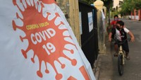 Anak-anak bermain sepeda di depan spanduk gerakan pencengahan COVID-19 di Desa Ilie Ulee Kareng, Banda Aceh, Aceh. ANTARA FOTO/SYIFA YULINNAS.