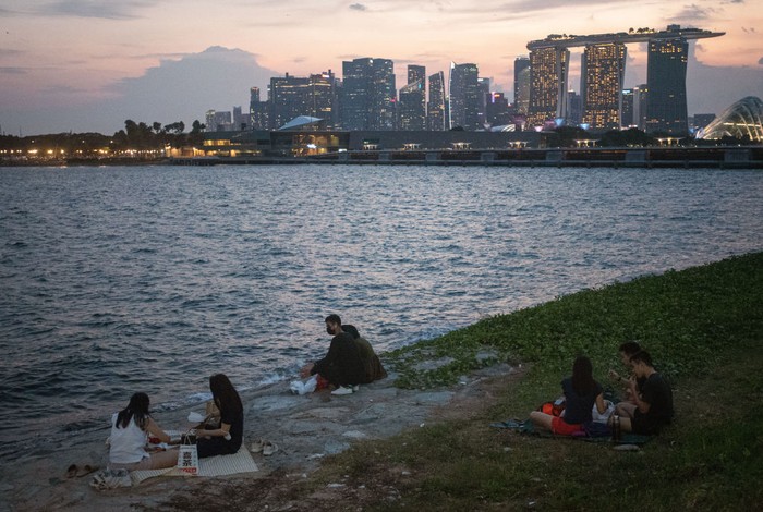 SINGAPORE, SINGAPORE - JUNE 06: People picnic on a breakwater at the Marina East Park on June 06, 2021 in Singapore. Facing a sudden spike in the number of locally transmitted COVID-19 infections, Singapore in May introduced new restrictions in a bid to avert widespread infections and also to prevent a full-blown lockdown, which would damage its recovering economy. The restrictions include a reduction in the cap on people who can gather to socialise from five to two. As a result, this phase of the pandemic has seen Singapore become populated with groups of two in public, a visual oddity in a city that is normally bustling with large groups of people who enjoy socialising outside in its tropical climate. (Photo by Feline Lim/Getty Images)