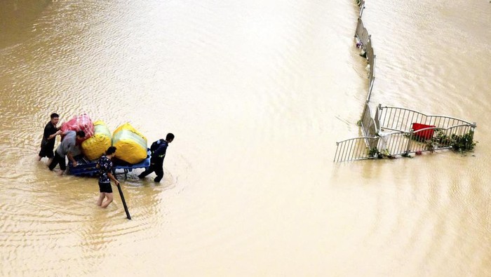 In this photo released by Xinhua News Agency, residents move their belongings across a flooded street in Zhengzhou in central Chinas Henan province on Wednesday, July 21, 2021. Chinas military has blasted a dam to release floodwaters threatening one of its most heavily populated provinces, as the death toll in widespread flooding rose to more than two dozens. (Zhu Xiang/Xinhua via AP)