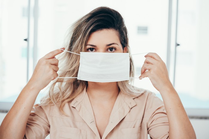 1215004440 Portrait of woman wearing surgical mask at home. Covid-19, coronavirus and quarantine concept.
