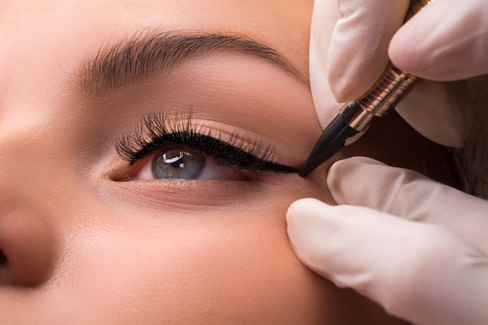 Permanent eye makeup close up shot. Cosmetologist applying tattooing of eyes. Makeup eyeliner procedure