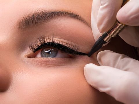 Permanent eye makeup close up shot. Cosmetologist applying tattooing of eyes. Makeup eyeliner procedure