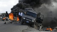 Polisi meninggalkan kendaraannya saat demonstrasi yang berubah menjadi kekerasan di mana pengunjuk rasa menuntut keadilan atas pembunuhan Presiden Jovenel Moise di Cap-Haitien, Haiti, Kamis (22/7/2021).